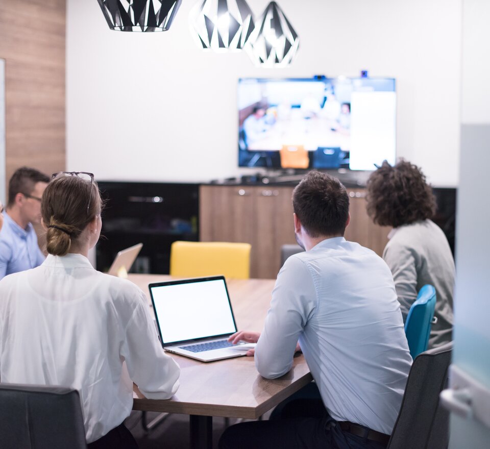 People sit in a hybrid meeting. | © Shutterstock