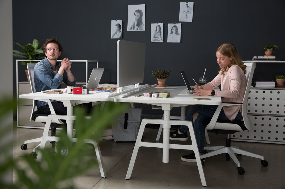 Zwei Personen arbeiten an ihren Schreibtischen.