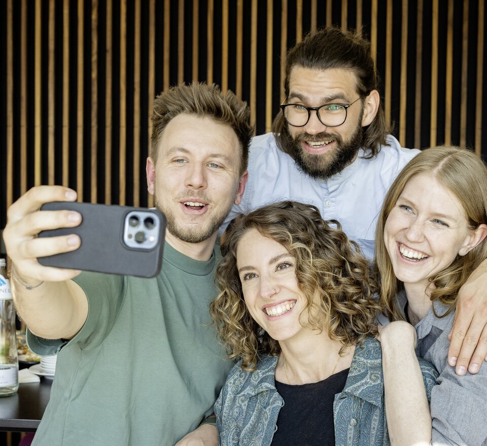 Vier Personen die gerade ein Selfie machen.