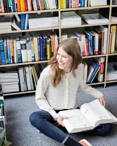 Person sitzt am Boden und liest ein Buch.