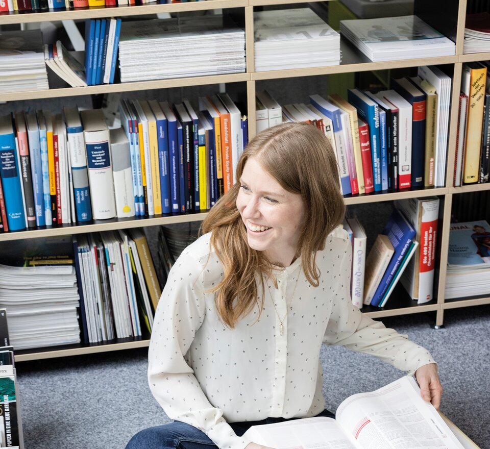 Person sitzt am Boden und liest ein Buch.