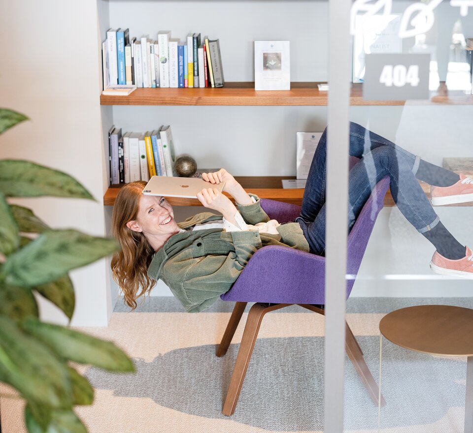 Person sitzt  kopfüber auf einem violetten Loungestuhl.