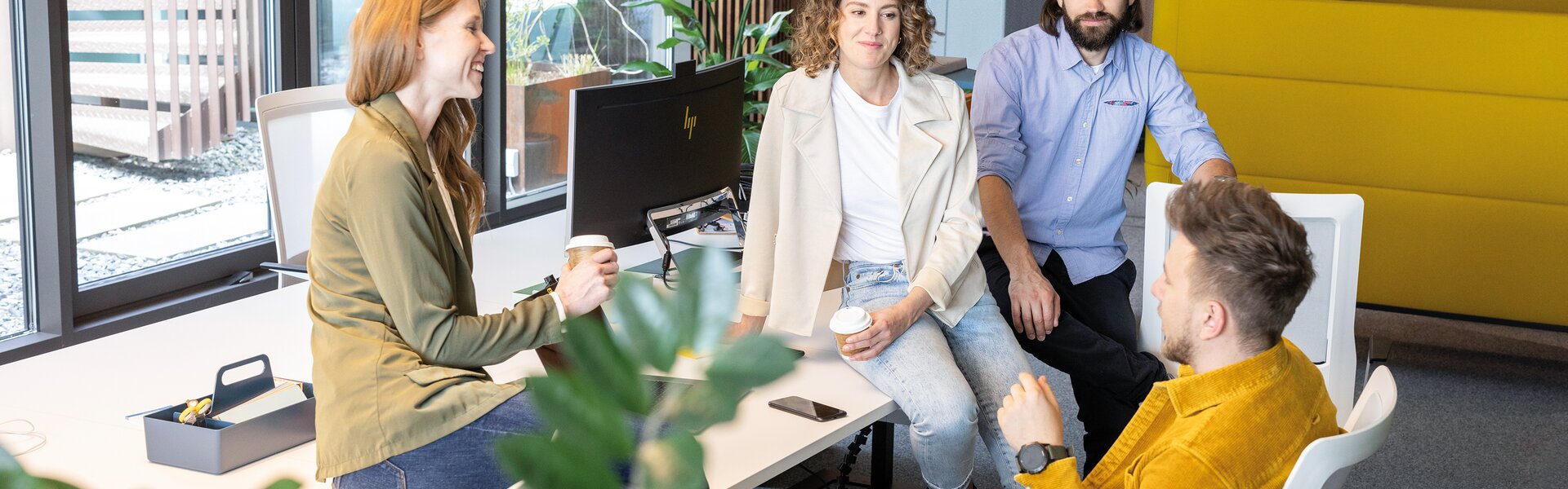 Four people sitting on a workbench talking to each other.