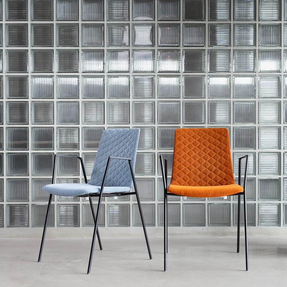 Ein blauer und ein roter Stuhl mit Design-Steppung vor Wand mit Glaskacheln