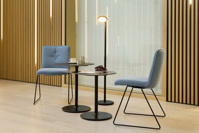 batch comfort skid-base chair Two blue padded skid-base chairs in front of a wooden wall.